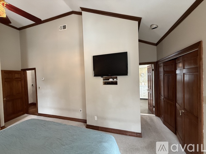 A bedroom with a bed and a television on the wall.