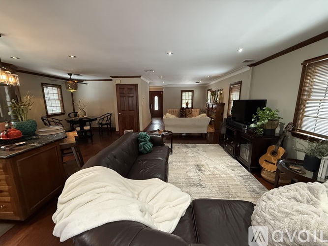 A living room with a black couch and a white blanket on it.