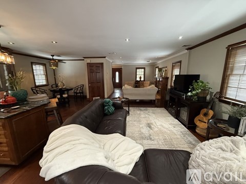 A living room with a black couch and a white blanket on it.