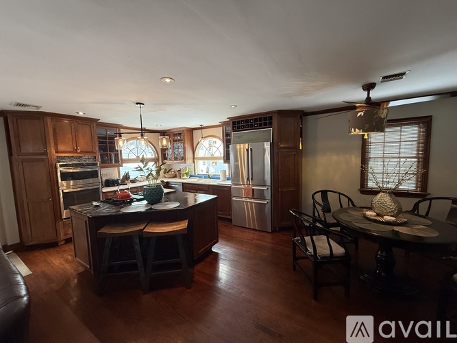 A kitchen with wooden cabinets and a large island with a bar stool.