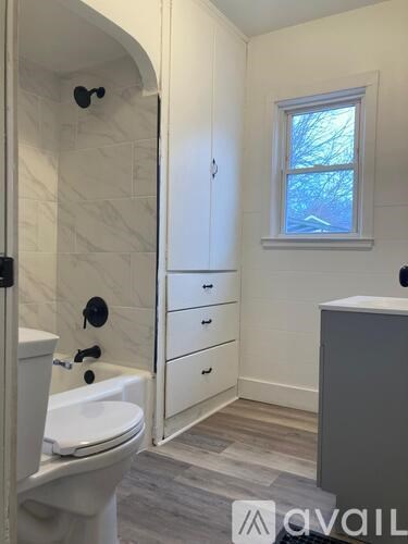 A bathroom with a toilet, sink, and a window.