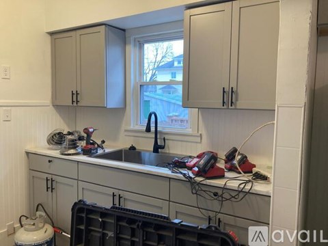 A kitchen with grey cabinets and a window overlooking a street.