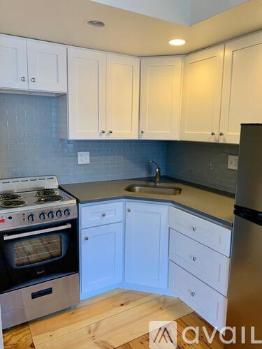 A kitchen with white cabinets and a black refrigerator.