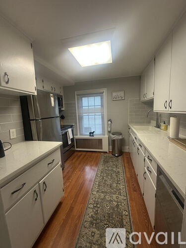 A kitchen with white cabinets and a rug on the floor.