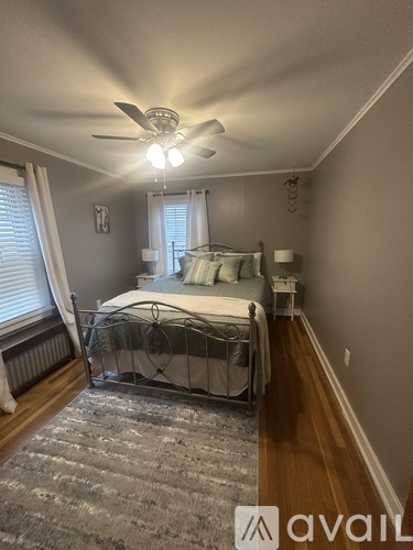 A bedroom with a bed, a ceiling fan, and a rug on the floor.