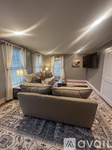 A living room with a large couch and a television mounted on the wall.