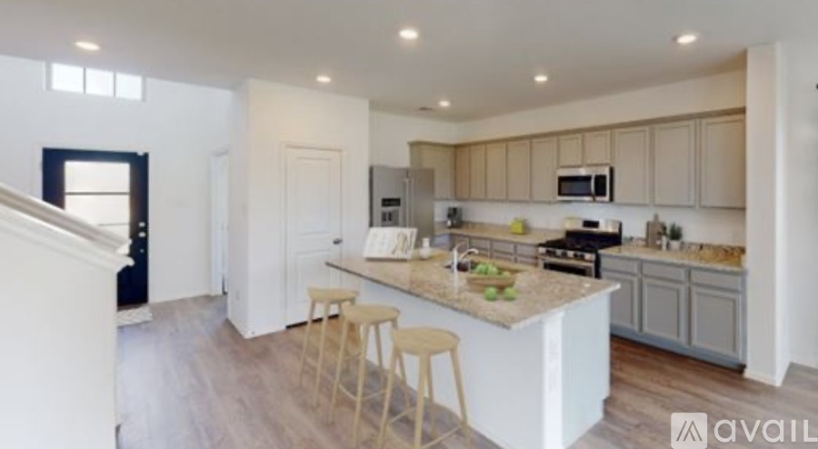 A kitchen with a white island and wooden stools.