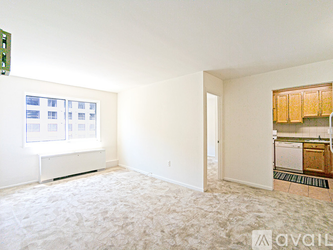 A room with a carpeted floor and a window with a view of a building.