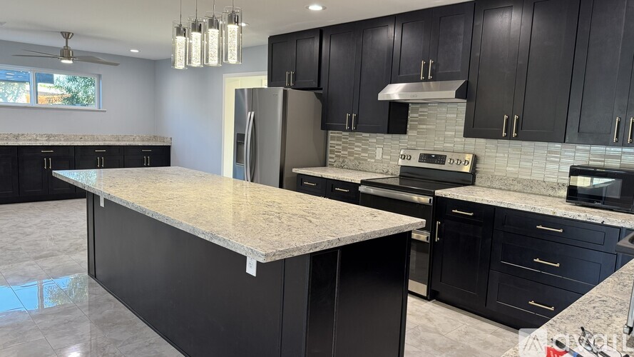 A modern kitchen with black cabinets and granite countertops.