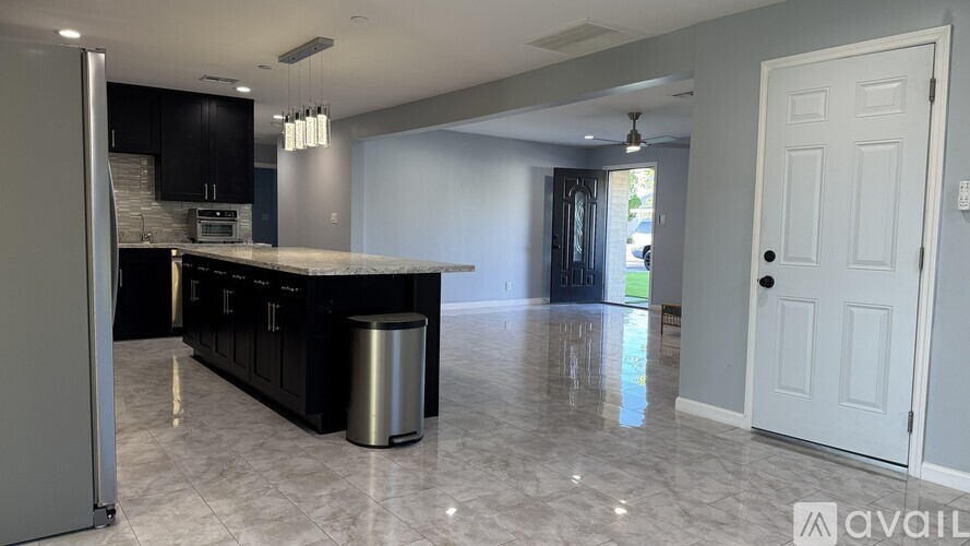 A kitchen with black cabinets and a marble floor.