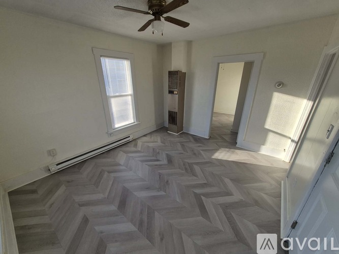 A room with a herringbone patterned floor and a white door.