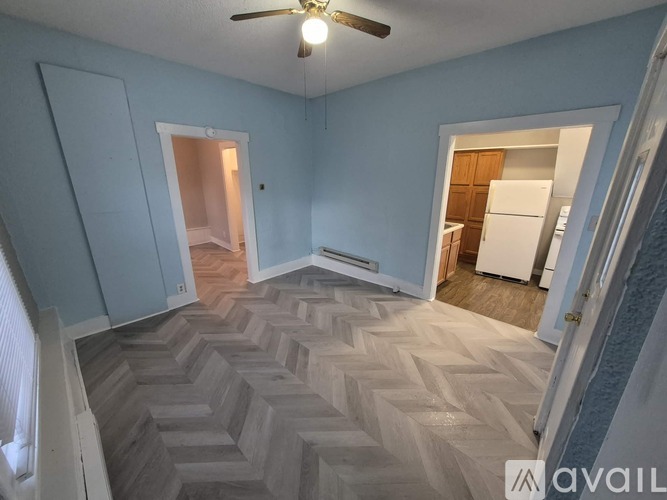 A room with a chevron patterned floor and a ceiling fan.
