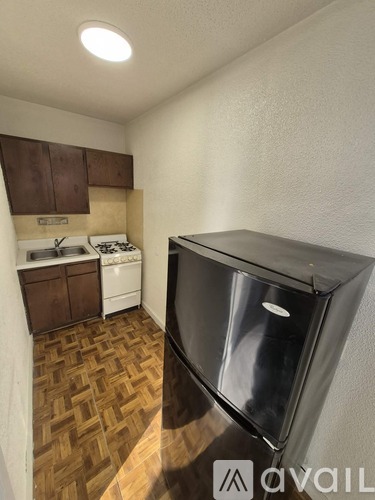A kitchen with a black fridge and wooden flooring.