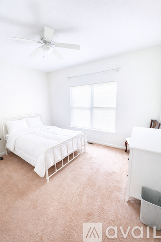 A white bedroom with a bed, dresser, and window.