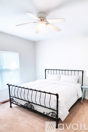 A bedroom with a white bed and a ceiling fan.