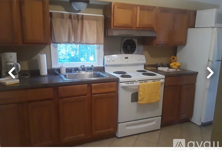 A kitchen with wooden cabinets and a white stove top oven.