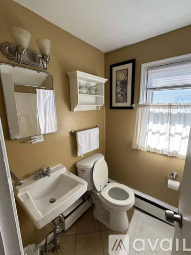 A white shower curtain hangs in a bathroom with a white tub.
