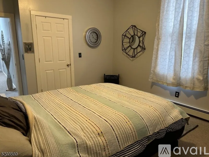 A bedroom with a bed, a clock, and a mirror on the wall.