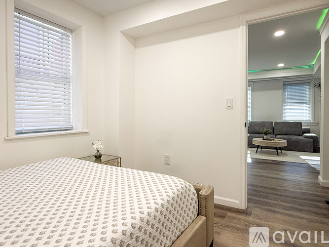 A bedroom with a bed, a nightstand, and a window.