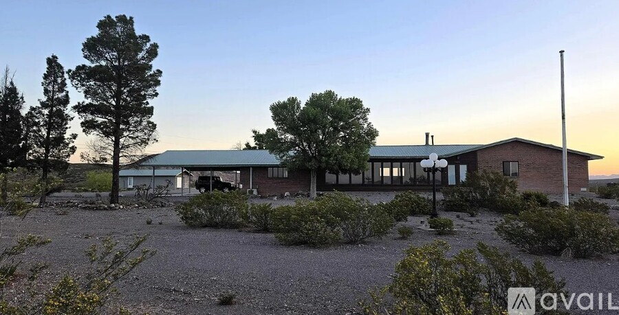 A house with a green roof is surrounded by trees and bushes.