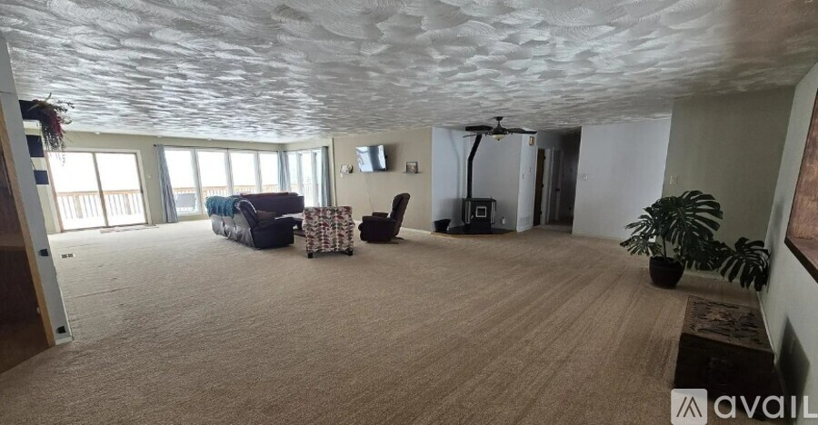 A spacious room with a carpeted floor and a ceiling fan.