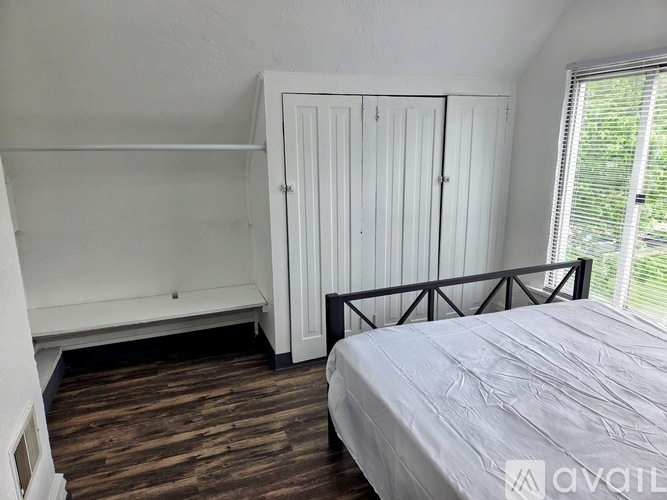 A bedroom with a bed, a wardrobe, and a window with blinds.