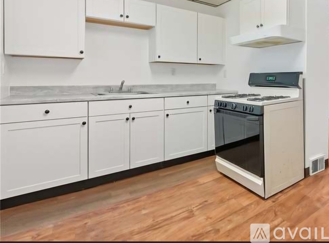 A kitchen with white cabinets and a wooden floor.