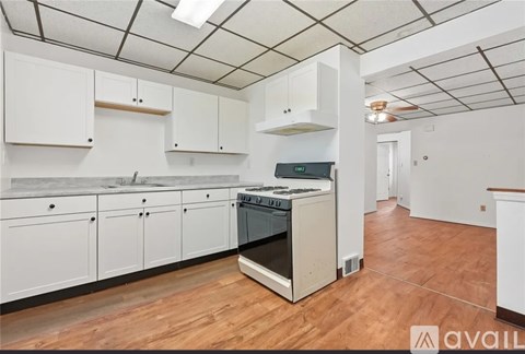 A kitchen with white cabinets and a wooden floor.