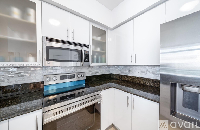 A modern kitchen with white cabinets and stainless steel appliances.