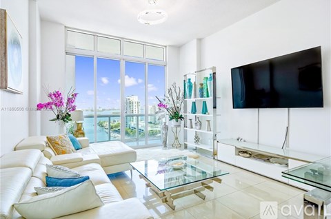 A living room with a glass coffee table and a flat screen TV mounted on the wall.