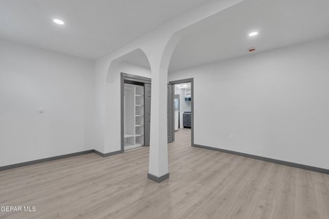 A spacious room with a wooden floor and white walls.