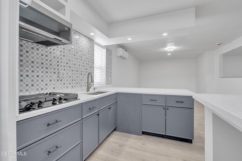A modern kitchen with a stove top oven and a tiled backsplash.