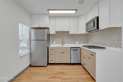 A kitchen with white cabinets and a wooden floor.
