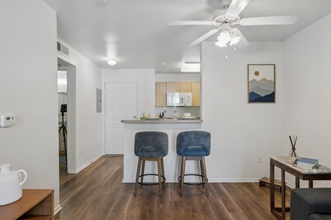 A kitchen with a white ceiling fan and two blue chairs.