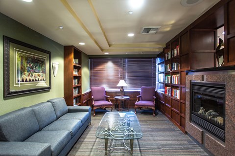 A living room with a grey couch, a coffee table, a fireplace, and a painting on the wall.