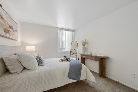 A bedroom with a bed, nightstand, and chair.