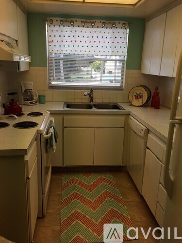 A kitchen with white cabinets and a green wall.