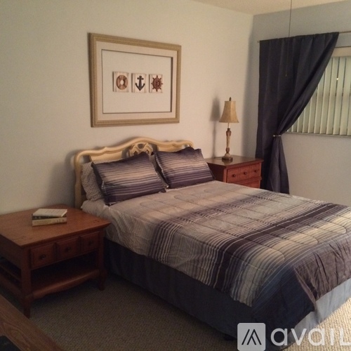 A bedroom with a bed, nightstand, and lamp.