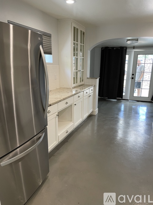 A kitchen with a stainless steel refrigerator and white cabinets.