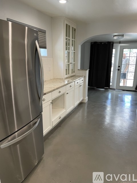 A kitchen with a stainless steel refrigerator and white cabinets.