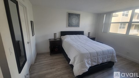 A bedroom with a large bed and a wooden floor.