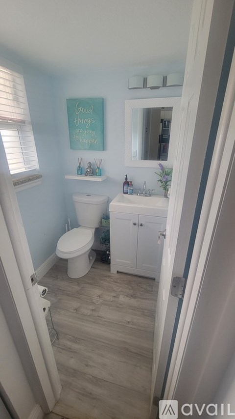 A bathroom with a toilet, sink, and a mirror.