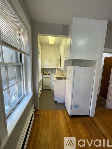 A kitchen with white appliances and wooden floors.