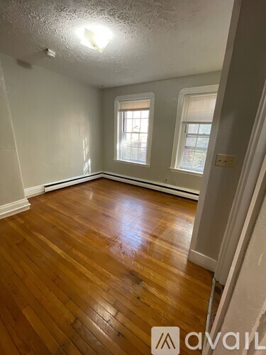 A room with wooden floors and two windows.