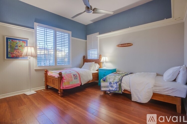 A bedroom with two beds and a ceiling fan.