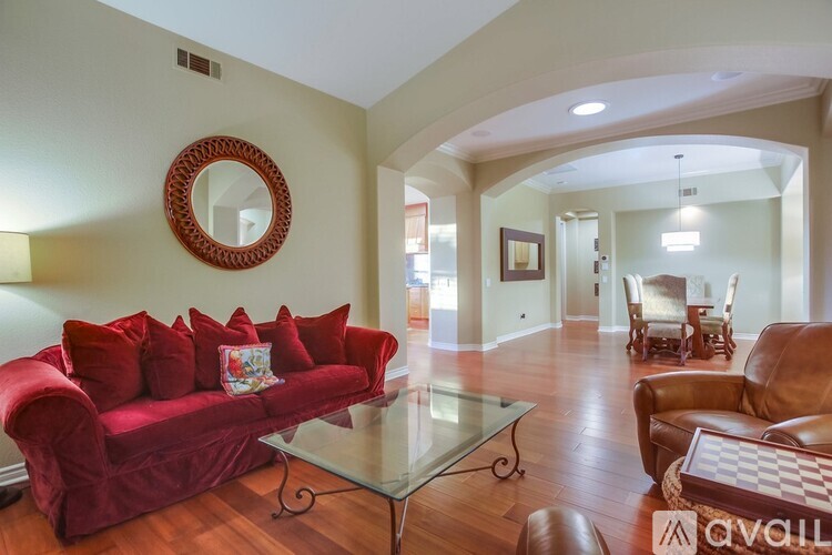 A living room with a red couch and a glass coffee table.