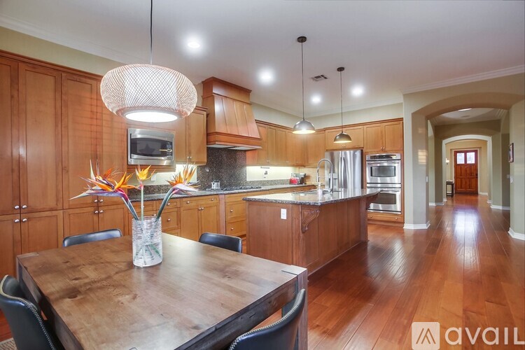 A kitchen with wooden cabinets and a wooden table with a vase on it.