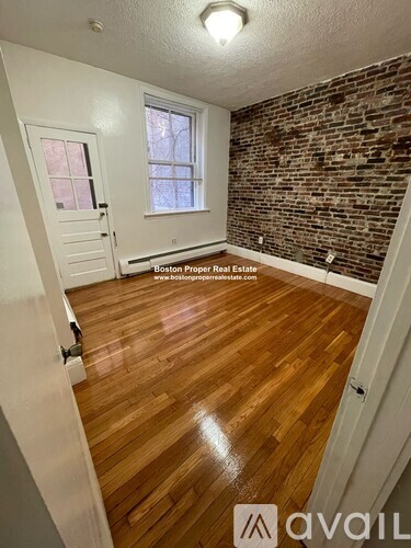 A room with wooden floors and a brick wall.