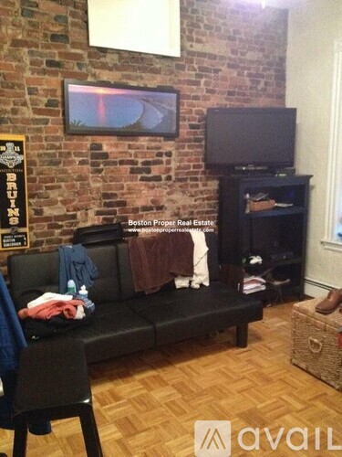A living room with a brick wall and a flat screen TV mounted on it.