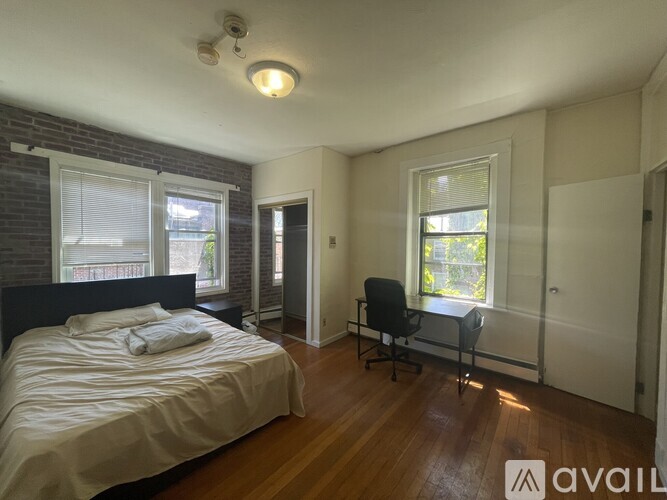 A bedroom with a bed, chair, and window.